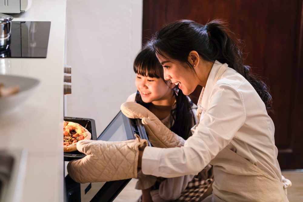 Asiatische junge Mutter und Tochter backen zu Hause